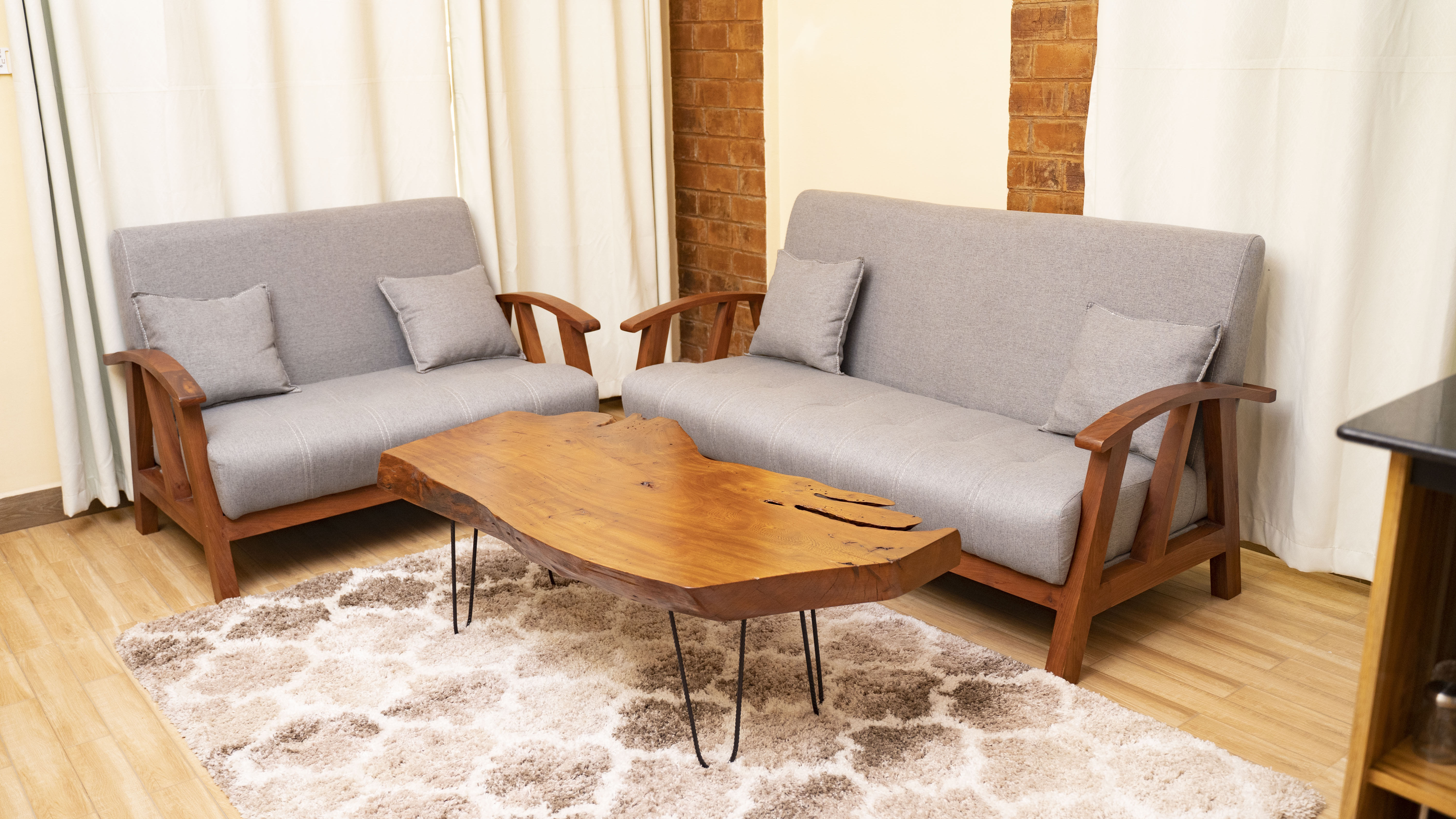 Sitting room — teak-frame sofas around a live-edge coffee table, opening into the kitchen beyond