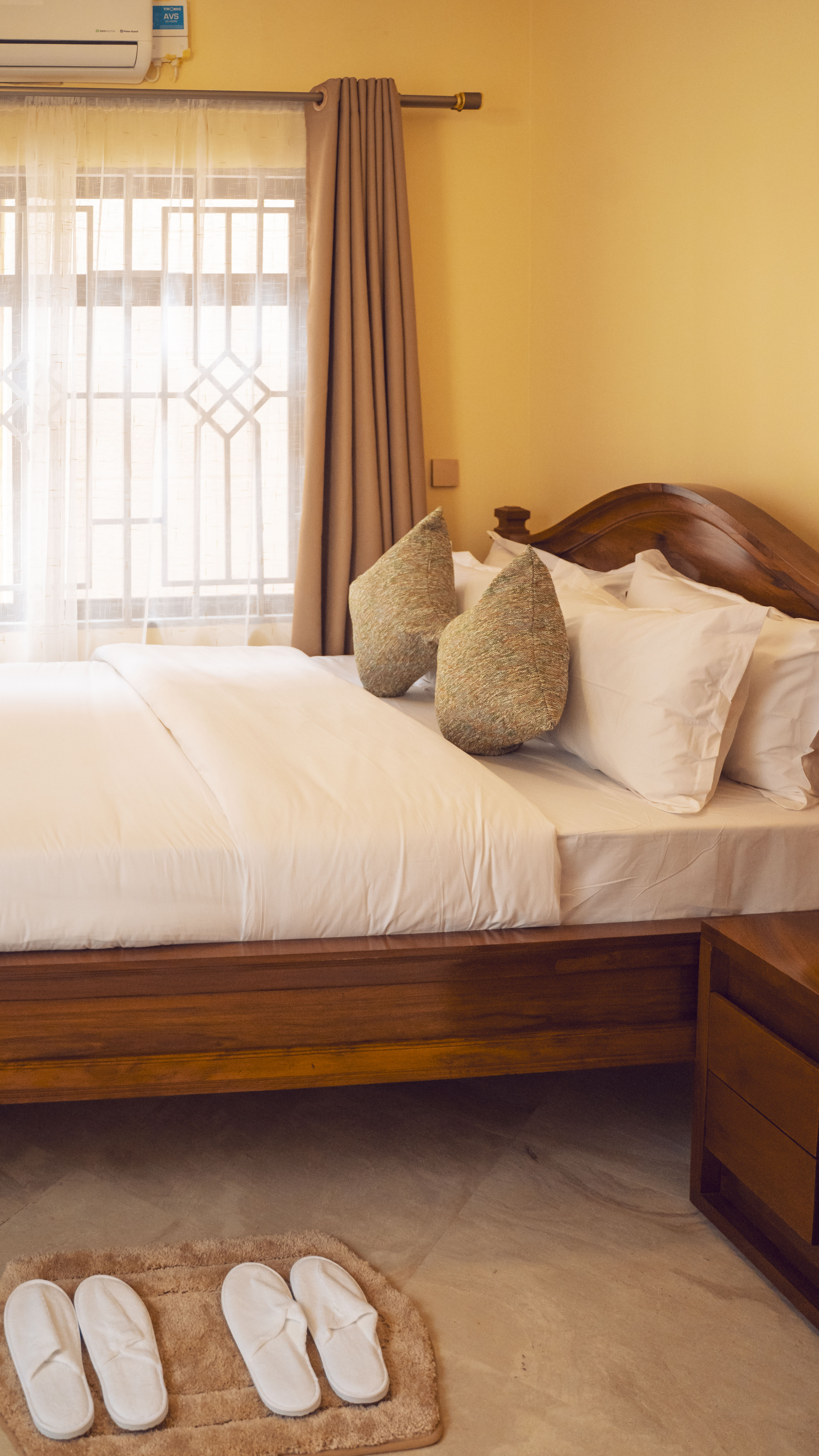 Master bedroom — hand-carved teak headboard, Egyptian-cotton linens and guest slippers on a bath mat