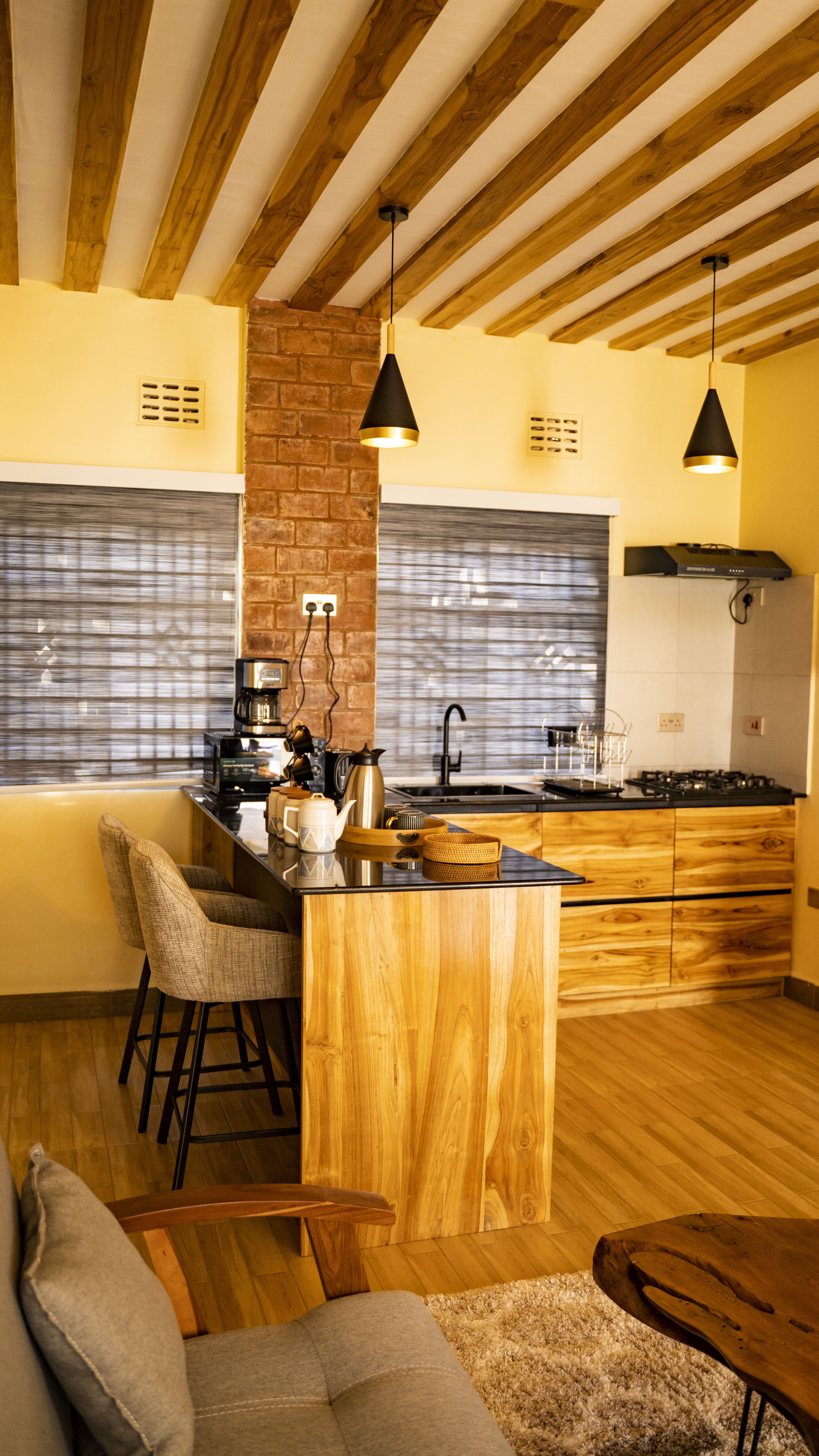 Open-plan kitchen at Lalashe Homes — handcrafted teak cabinetry, black granite countertops and exposed timber ceiling beams